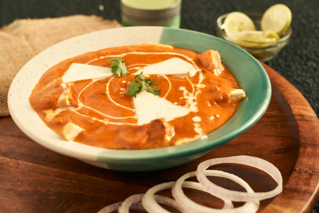 Delicious bowl of Indian butter chicken garnished with cream and cilantro, perfect for dinner.